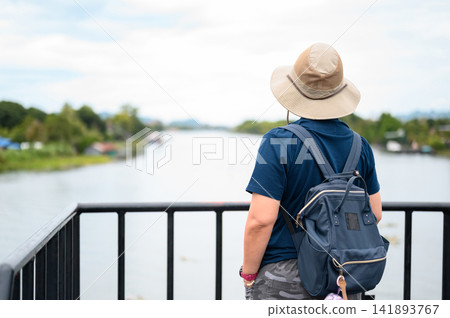 Traveler wearing hat standing on balcony and enjoying beautiful river view during summer trip. Traveler wearing hat standing on balcony and enjoying beautiful river view during summer trip. 141893767