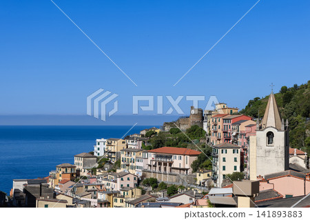Riomaggiore in Liguria, Italy with church and castle towers anchoring dense rooftops Riomaggiore in Liguria, Italy with church and castle towers anchoring dense rooftops 141893883