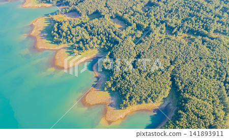 Top down aerial view of bright turquoise water of Lake Plastiras meeting dense green forest along jagged shoreline in Greece Top down aerial view of bright turquoise water of Lake Plastiras meeting dense green forest along jagged shoreline in Greece 141893911