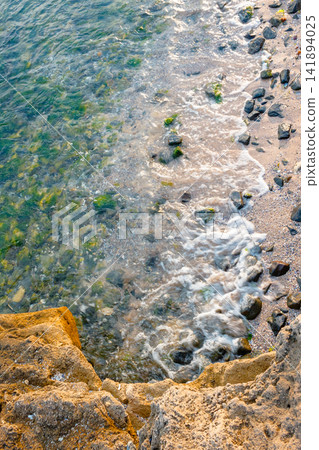 rock texture at the sea. ocean coast background. transparent water. calm wave and seaweed rock texture at the sea. ocean coast background. transparent water. calm wave and seaweed 141894025