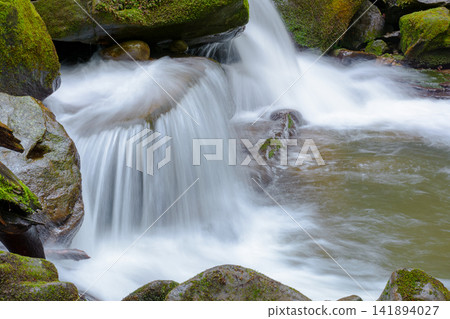 small waterfall closeup. beautiful cascade on the water stream with mossy rock 141894027