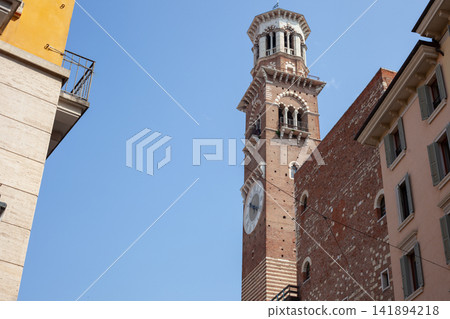 Torre dei Lamberti Clock Tower Rising above Buildings with Blue Sky in Verona Italy Torre dei Lamberti Clock Tower Rising above Buildings with Blue Sky in Verona Italy 141894218