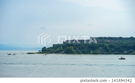 Medieval fortress rising above a green island surrounded by Lake Garda in northern Italy. Concept of history, travel, nature and cultural heritage 141894342