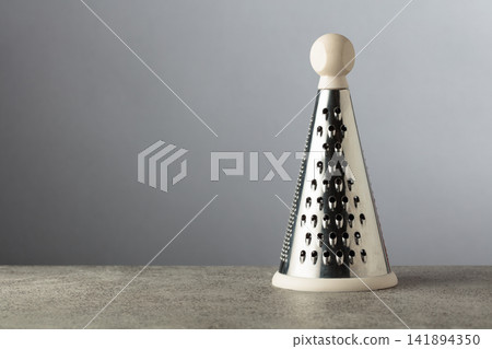 Modern kitchen grater on a grey stone table. Modern kitchen grater on a grey stone table. 141894350