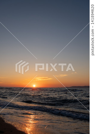 Bright orange sun touching sea horizon line at twilight dusk Bright orange sun touching sea horizon line at twilight dusk 141894620