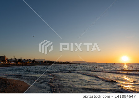 Scenic sunset over wavy sea near coastal resort shoreline 141894647
