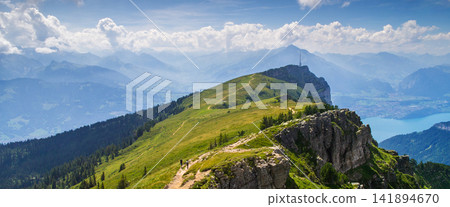 Mountain Panorama with Alpine Trail, Lake, Clouds, and Hikers 141894670