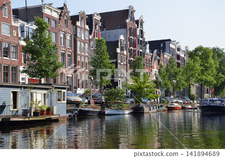 Amsterdam Canal Houses and Boats on a Sunny Waterfront Amsterdam Canal Houses and Boats on a Sunny Waterfront 141894689