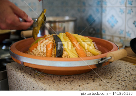 Authentic Moroccan couscous with vegetables served in a terracotta dish, homemade North African meal Authentic Moroccan couscous with vegetables served in a terracotta dish, homemade North African meal 141895153