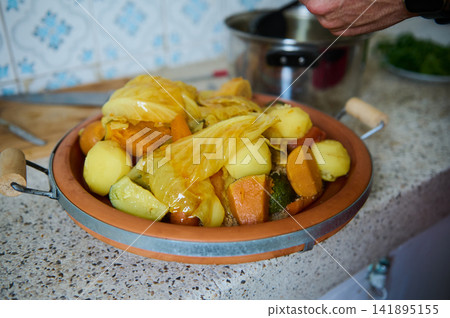 Authentic Moroccan couscous dish with vegetables served in a ceramic plate on a kitchen counter Authentic Moroccan couscous dish with vegetables served in a ceramic plate on a kitchen counter 141895155