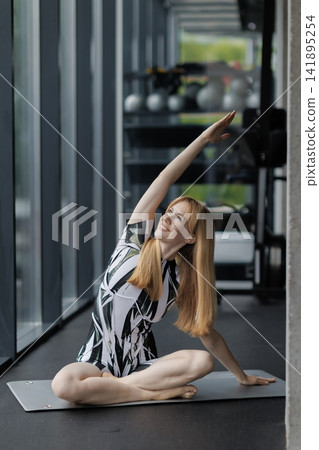 Woman stretching in yoga pose on mat in gym Woman stretching in yoga pose on mat in gym 141895254