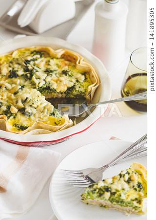 Savory spinach and feta cheese quiche served on a white plate with forks and a glass of white wine Savory spinach and feta cheese quiche served on a white plate with forks and a glass of white wine 141895305