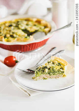 Freshly Baked Broccoli Quiche Slice on a Plate with Whole Quiche Background and Tomato Freshly Baked Broccoli Quiche Slice on a Plate with Whole Quiche Background and Tomato 141895308