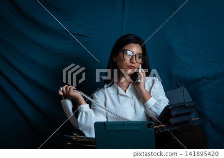 Woman multitasking with mobile phone and landline Woman multitasking with mobile phone and landline 141895420
