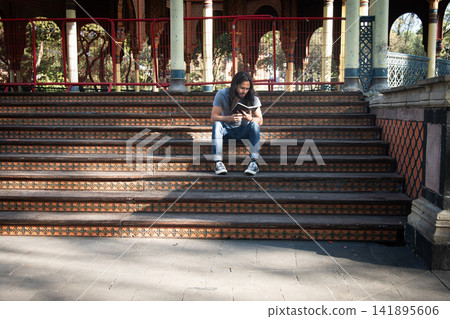Young man reading book on morisco kiosk steps Young man reading book on morisco kiosk steps 141895606