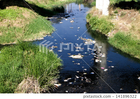 Plastic and other debris floating on river from city Plastic and other debris floating on river from city 141896322
