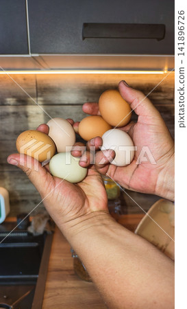 Hands holding an assortment of fresh organic chicken eggs, showcasing natural colors and promoting healthy eating and sustainable farming in a kitchen environment Hands holding an assortment of fresh organic chicken eggs, showcasing natural colors and promoting healthy eating and sustainable farming in a kitchen environment 141896726