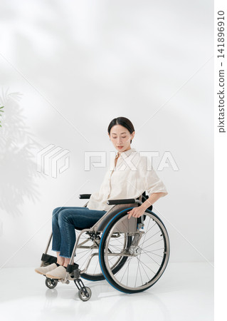 A woman in her 40s sitting in a wheelchair. A woman in her 40s sitting in a wheelchair. 141896910