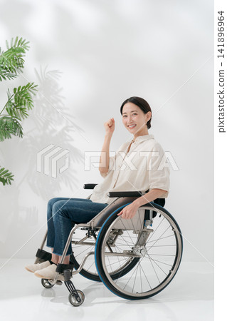 A woman in her 40s sitting in a wheelchair. A woman in her 40s sitting in a wheelchair. 141896964