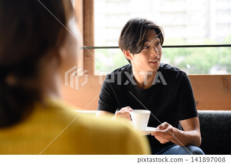 一名男子手拿咖啡杯,正在與一名女子交談。 一名男子手拿咖啡杯,正在與一名女子交談。 141897008