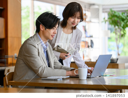 A man and a woman working together on a laptop computer. A man and a woman working together on a laptop computer. 141897053