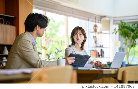 A man and a woman having a meeting using a tablet and a laptop. A man and a woman having a meeting using a tablet and a laptop. 141897062