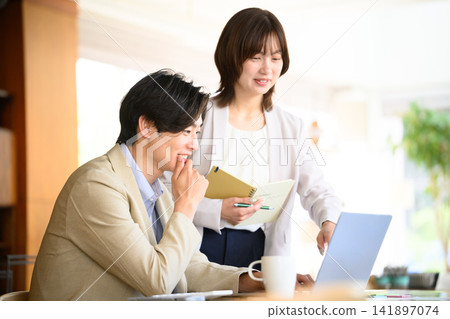 一男一女一邊看著電腦一邊交談。 141897074