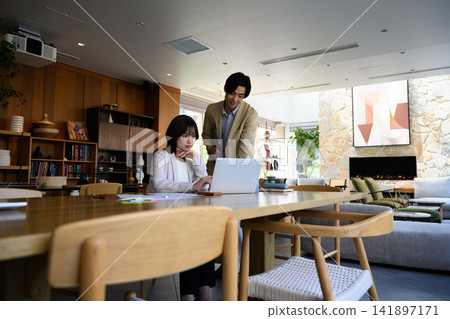 A man watching over someone working on a computer. A man watching over someone working on a computer. 141897171