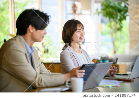 A man and a woman talking while looking at a tablet. A man and a woman talking while looking at a tablet. 141897174