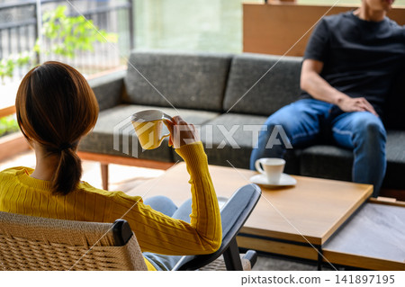 A man and woman relaxing at a cafe, enjoying their coffee. A man and woman relaxing at a cafe, enjoying their coffee. 141897195