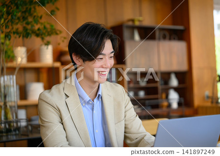 一位微笑的男子坐在電腦前。 141897249