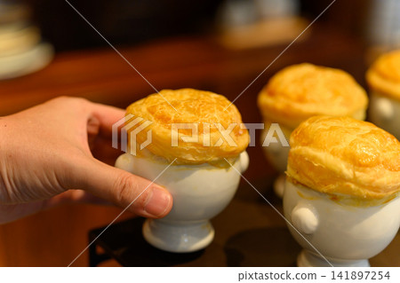 A piping hot soup covered with pastry dough A piping hot soup covered with pastry dough 141897254