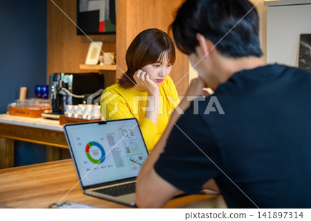一位女士在咖啡館裡看著筆記型電腦上的圖表,陷入了沉思。 一位女士在咖啡館裡看著筆記型電腦上的圖表,陷入了沉思。 141897314