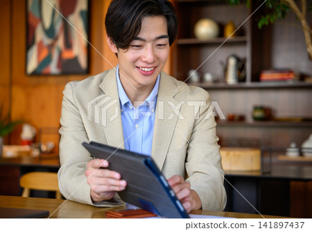 一名男子在商務場合手持平板電腦。 一名男子在商務場合手持平板電腦。 141897437