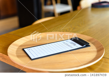 桌上放著一張收據和一個木托盤。 桌上放著一張收據和一個木托盤。 141897439