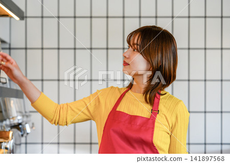 Female store clerk picking up items from the shelves Female store clerk picking up items from the shelves 141897568