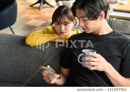 A man and a woman looking at their smartphones on a sofa. A man and a woman looking at their smartphones on a sofa. 141897961