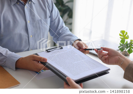 Businessman Handing Over Contract and Pen for Signature in Workplace. Businessman Handing Over Contract and Pen for Signature in Workplace. 141898158