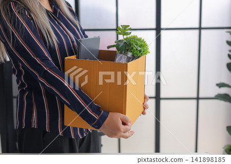 Businesswoman Carrying Cardboard Box with Personal Belonging in Office Businesswoman Carrying Cardboard Box with Personal Belonging in Office 141898185