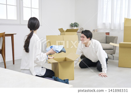 A man apologizing during a move and a woman packing her belongings. A man apologizing during a move and a woman packing her belongings. 141898331