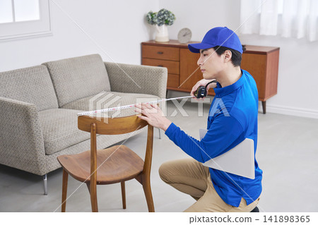 A worker measuring the size of a chair A worker measuring the size of a chair 141898365