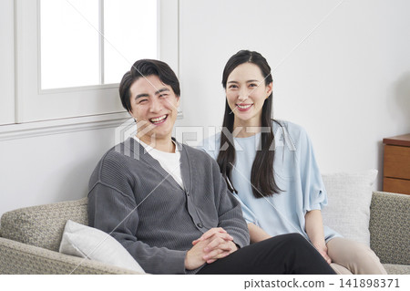 Portrait of a middle-aged couple in their living room, looking directly at the camera. Portrait of a middle-aged couple in their living room, looking directly at the camera. 141898371