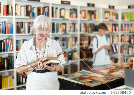 In bookstore senior woman choose book In bookstore senior woman choose book 141898460