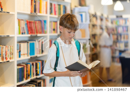 Teenage boy choosing book in bookstore Teenage boy choosing book in bookstore 141898467