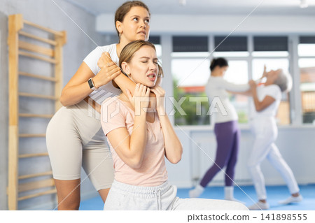 Woman and girl in gym perform basic elements of krav maga self-defense system. Woman and girl in gym perform basic elements of krav maga self-defense system. 141898555