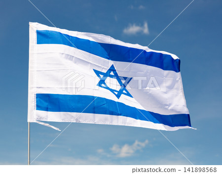 National flag of Israel flies on flagpole against blue sky National flag of Israel flies on flagpole against blue sky 141898568