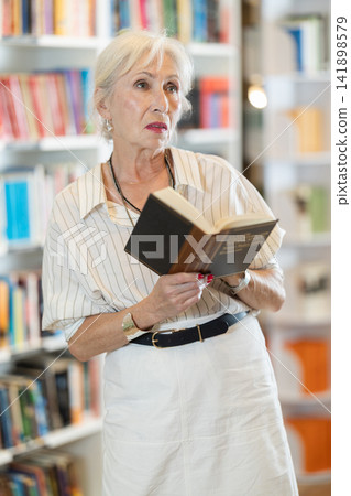 Senior woman choosing books in large bookstore Senior woman choosing books in large bookstore 141898579