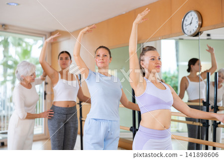 Female ballet instructor adjusting students form in dancing school Female ballet instructor adjusting students form in dancing school 141898606