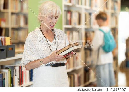 Elderly woman choosing book in bookstore Elderly woman choosing book in bookstore 141898607