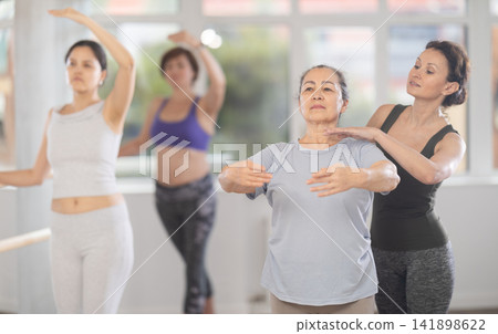 Ballet choreographer instructing senior woman in basic ballet techniques Ballet choreographer instructing senior woman in basic ballet techniques 141898622